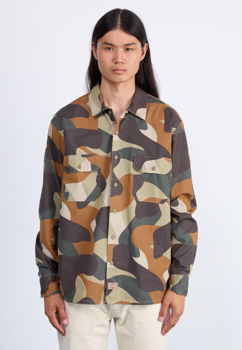 Camouflaged Hemd mit braunen, grünen und beigen abstrakten Mustern. Mit durchgehender Knopfleiste, zwei Brusttaschen und einem klassischen Kragen. Baumwollstoff.
