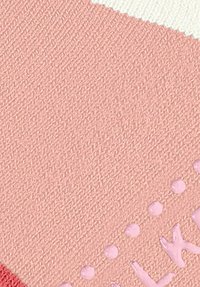 Tissu texturé en rose avec un design géométrique, comportant des points surélevés et des lettres en rose clair, contre une section blanche contrastée.