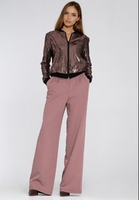 Kurtka bomberka z cekinami w ciemnym różu z czarną lamówką, zestawiona z wysokim stanem i szerokimi nogawkami spodni wykonanych z miękkiego różowego materiału. Gładka faktura.