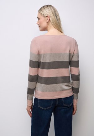 Pull vue de face en rose, beige et rayures gris foncé. Matière en tricot douce, col rond et ourlet ajusté. Associé à un jean bleu foncé.