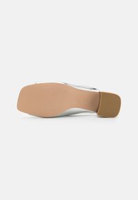Sole di scarpa con tacco alto caratterizzata da una base in gomma beige e una parte superiore liscia in argento, con un design a profilo basso e punta arrotondata.