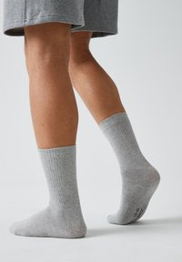 Graue gerippte Socken aus einem Baumwollgemisch, mit einer leichten Textur, in mittlerer Schafthöhe und mit einem Logo an der Sohle.