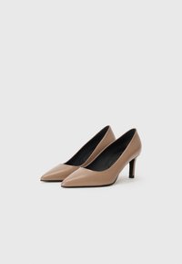 Escarpins beiges en cuir à bout pointu avec une texture lisse et un talon aiguille noir fin, présentant un design à découpe basse sur les côtés.