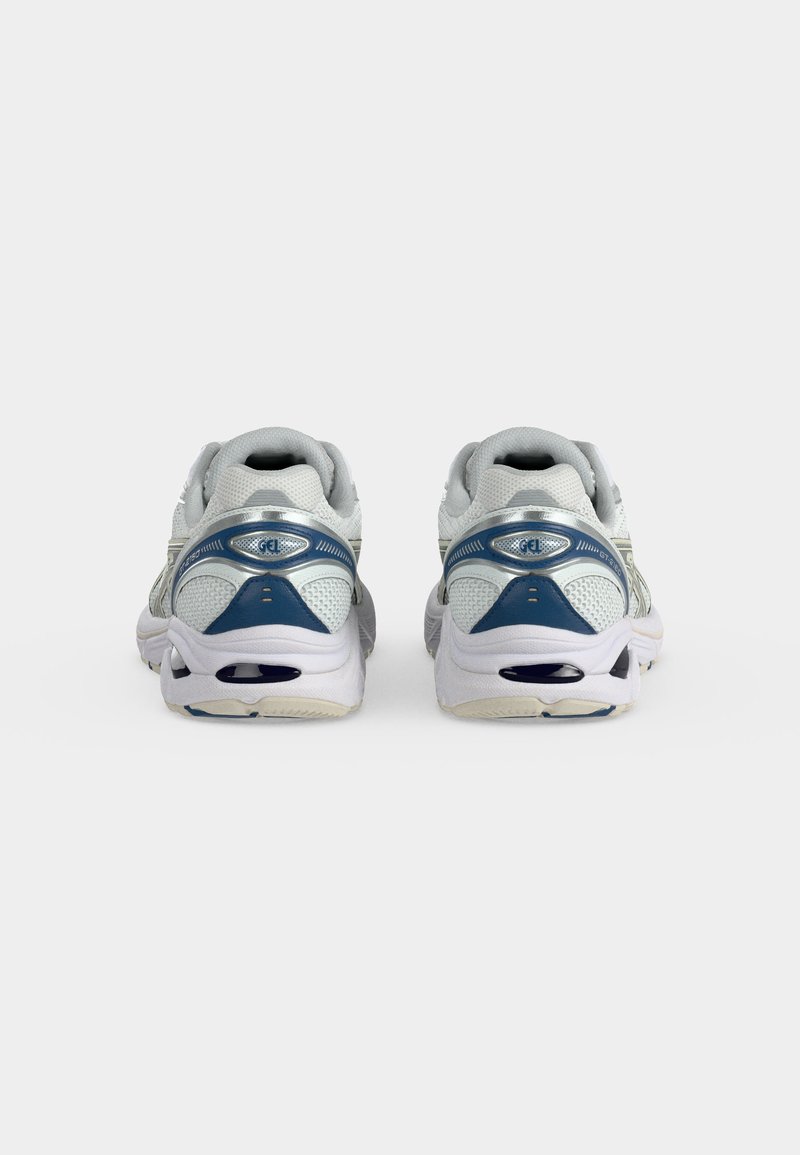 Par de zapatillas deportivas blancas y azules vistas desde atrás sobre un fondo blanco liso.