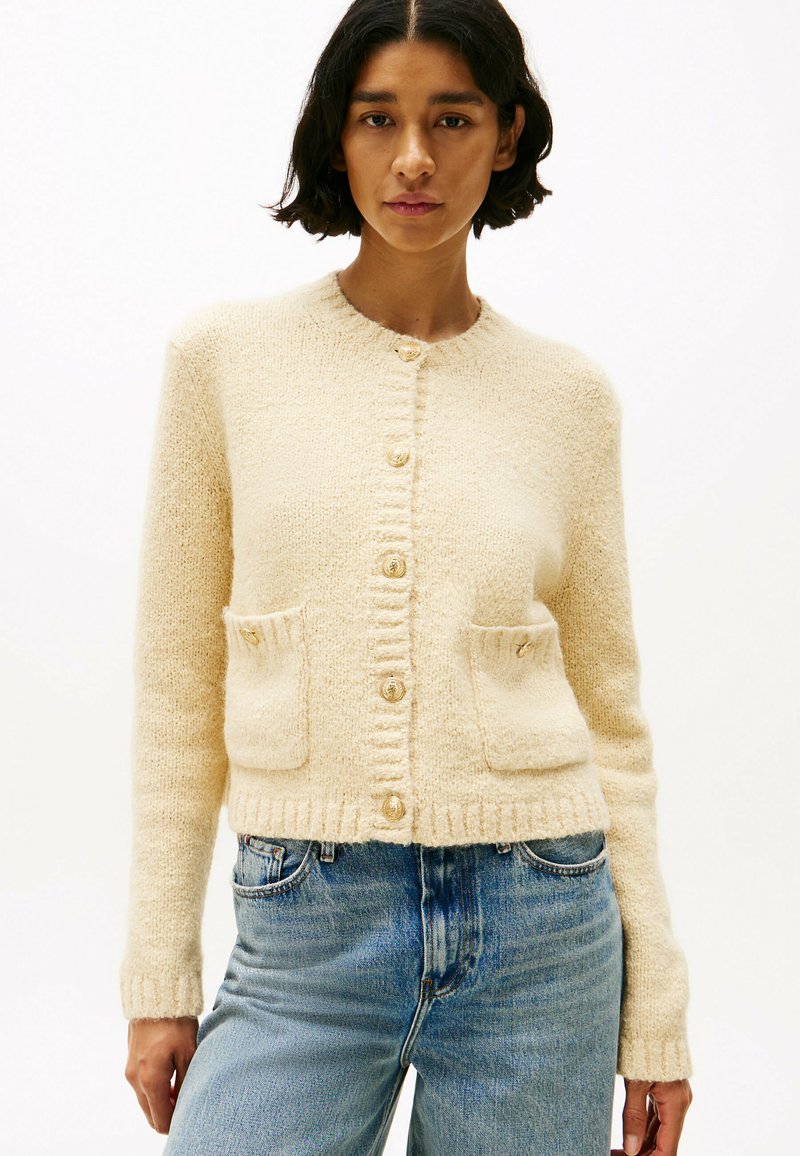 Crème-kleurige cardigan van zacht, gestructureerd materiaal, met een ronde halslijn, gouden knopen en twee voorzakken.