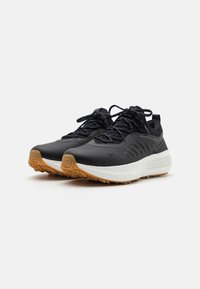 Black running shoes with a textured upper, reflective accents, white midsole, and rubber outsole. Feature flat laces and padded collar.