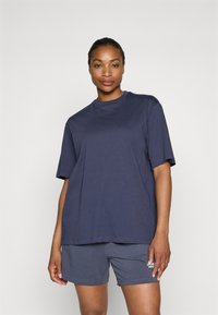 Navy blue cotton t-shirt with short sleeves, round neckline, and loose fit, paired with dark gray shorts featuring a small logo.