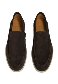 Zapatos de ante marrón oscuro de tipo slip-on con puntera redondeada, costuras mínimas y suela de goma de color claro. Forro interior suave.