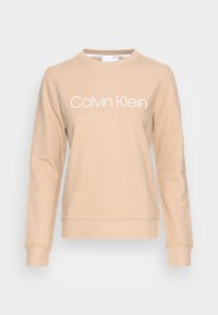 Felpa beige con maniche lunghe, collo rotondo, polsini e orlo a coste. Caratterizzata dal logo bianco "Calvin Klein" sul davanti. Tessuto dalla superficie liscia.
