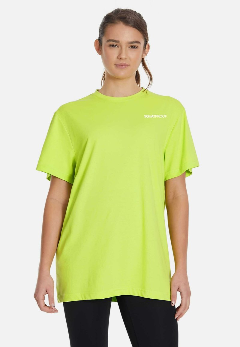 Neona zelena kratkotrajna majica s kratkimi rokavi, izdelana iz mehkega blaga, z okroglim izrezom in majhnim belim logotipom "SQUATPROOF" na zgornji levi strani.