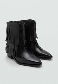 Botines negros de cuero, con detalles de flecos a los lados, punta afilada, tacón bajo tipo bloque y un acabado suave.