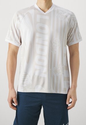 Homme portant un maillot de sport à manches courtes gris clair avec le texte "LONDON" et un short bleu.