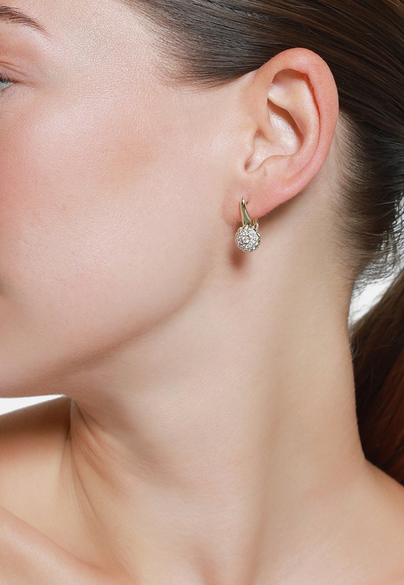 Boucles d'oreilles en or en forme de créole, ornées d'un amas sphérique de strass transparents, mettant en valeur une surface brillante et des détails raffinés.