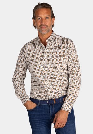 Witte overhemdd met bruine en oranje cirkelpatronen. Heeft een klassieke kraag, lange mouwen en een getailleerde pasvorm. Gecombineerd met denim.