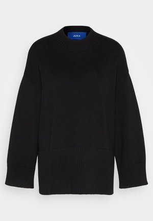 Svart stickad tröja med rund halsringning, ribbade manschetter och nederkant, samt en avslappnad passform. Materialet verkar mjukt och texturerat. Varumärkesetikett synlig.