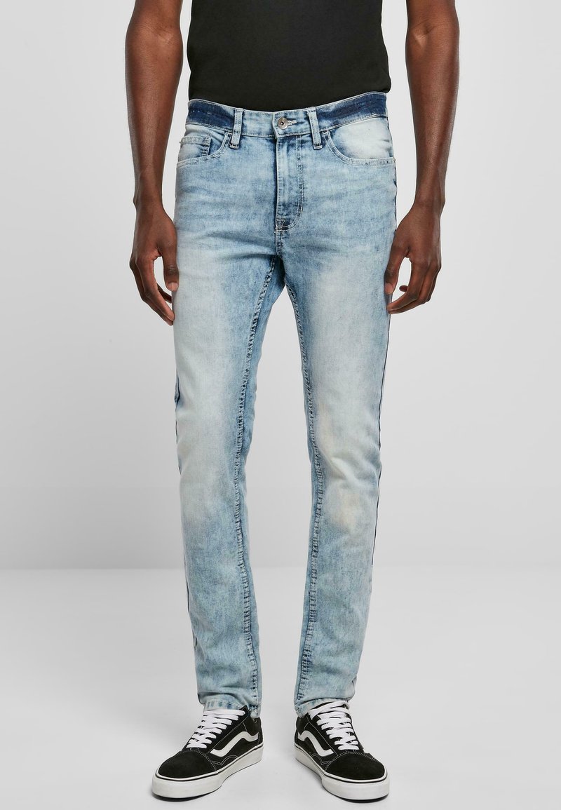 Jeans de mezclilla azul claro con un corte slim, diseño deslavado, cinco bolsillos y una cinturilla oscura, combinados con zapatillas en blanco y negro.