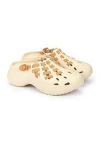 Zuecos de plástico beige con diseño trenzado; presentan recortes para ventilación y suela plana de goma. Detalles en marrón claro en las correas.