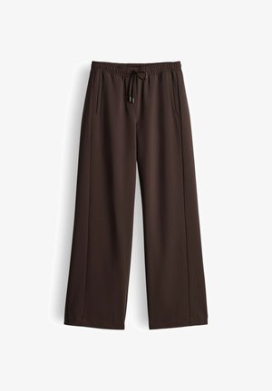 Pantaloni marroni a gamba larga realizzati in tessuto liscio, con vita elastica e coulisse, e due tasche laterali.