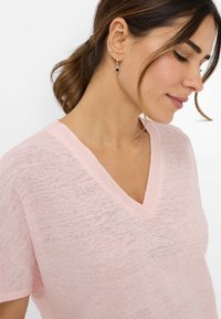 Lyserød V-hals t-shirt lavet af et blødt, tekstureret stof. Har korte ærmer og en diskret ribbet halsudskæring.