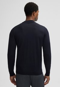 Marineblauer Pullover mit langen Ärmeln, geripptem Halsausschnitt und Bündchen, strukturiertem Strickmuster und schmalem Saum, aus einem weichen Stoff gefertigt.