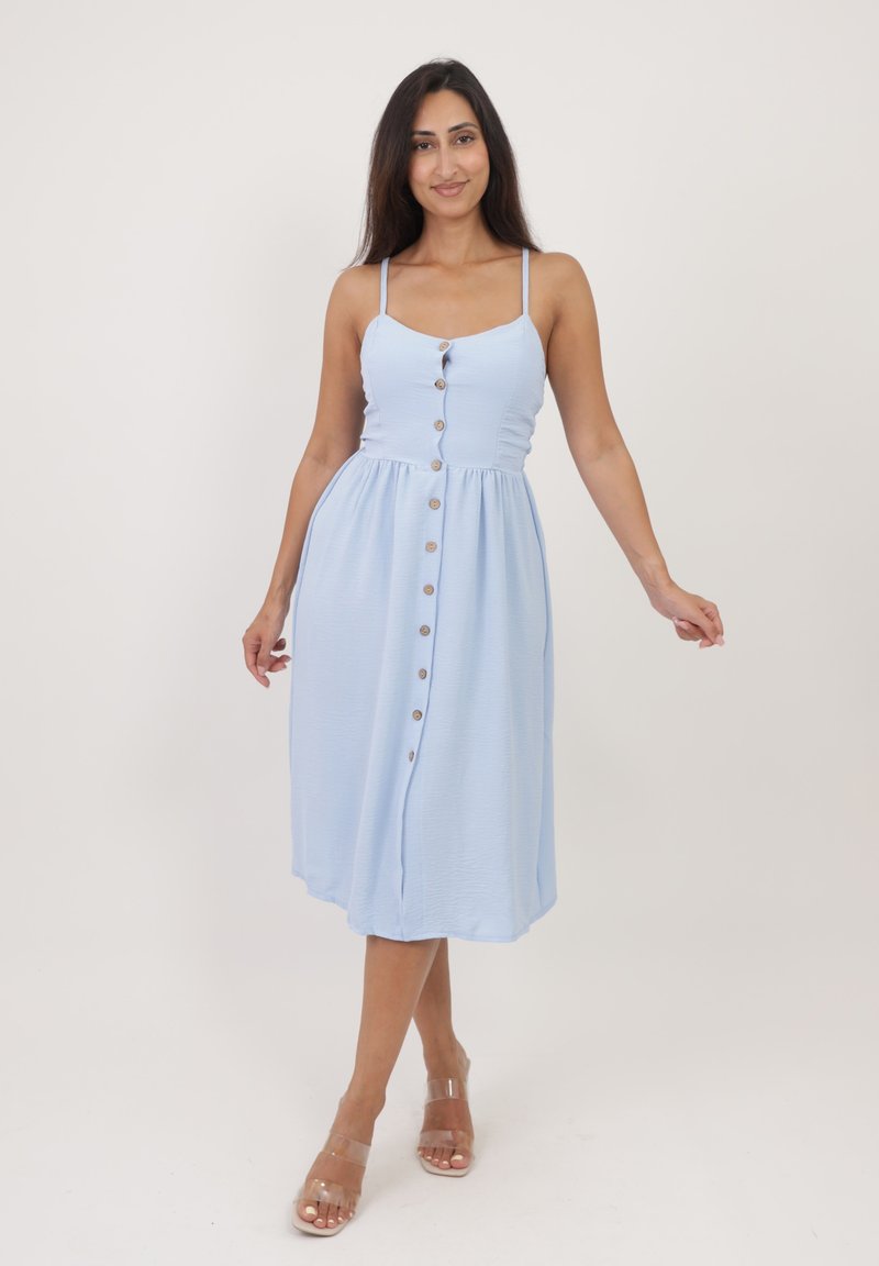 Vestido midi azul claro con tirantes finos, cierre frontal de botones y cintura fruncida. Presenta una tela texturizada y una silueta simple y fluida.