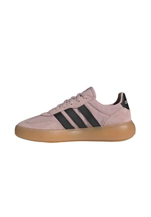 Niskie sneakersy z różowego zamszu i tkaniny z czarnymi paskami oraz grubą jasnobrązową podeszwą, widziane z boku na białym tle.