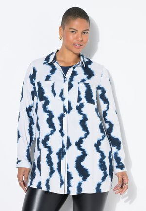 Camisa de manga larga en blanco con patrones ondulados azules, con un cierre de botones en la parte delantera y dos bolsillos en el pecho; tejido ligero y un corte holgado.