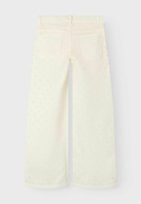 Jean large blanc avec une surface texturée arborant de petits motifs floraux discrets. Comprend deux poches arrière et des détails cousus.