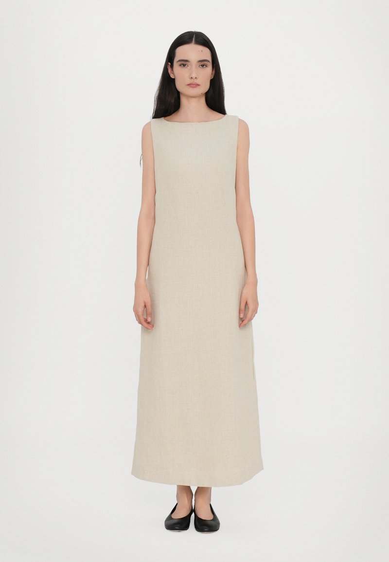 Beige ilmanhihais maxi-mekko, jossa on neliön muotoinen kaula-aukko, valmistettu teksturoidusta kankaasta. Yhdistetty mustiin mataliin kenkiin. Minimalistinen muotoilu, suora siluetti.