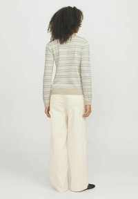 Rö Stripebeige kampsärgid pastellivärvi triipudega, peenelt vöödiga ja ribaga mansettidega, koos laia jala kreemiliste pükstega.