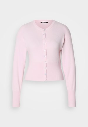 Svijetloružičasti kardigan od mekog pletenja, s okruglim izrezom, dugim rukavima, rebrastim manžetama i prednjim kopčanjem na dugmiće nalik biserima.