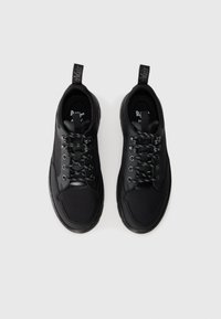 Pair of black low-top sneakers with patterned laces and branded pull tabs, viewed from above on a plain white background.