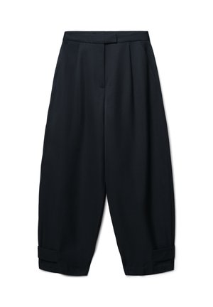 Pantaloni neri, oversize, realizzati in tessuto morbido, con pieghe, tasche laterali e orli con risvolto. Vita sartoriale senza chiusure visibili.