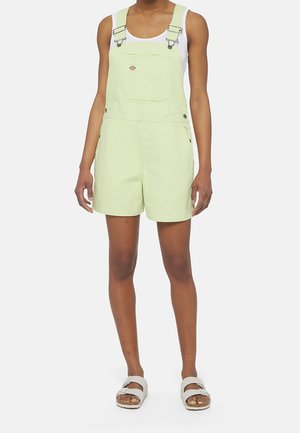 Lysegrønne denim-overalls med justerbare stropper og forlommer, kombineret med en hvid tanktop og lyse sandaler.