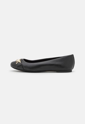 Schwarzer flacher Lederschuh mit einem goldfarbenen Metallverschluss auf der Spitze, mit niedrigem Absatz und rundlicher Zehenform.