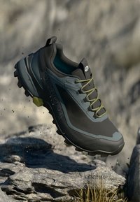 Zapatilla de trail running Scarpa, en gris carbón y negro, con cordones verdes, suela acolchada, detalles texturizados y un destacado logotipo en el lateral.