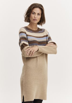 Strickkleid in Beige mit einem gemusterten Einsatz, das braune, blaue und cremefarbene Streifen zeigt. Lange Ärmel, lockerer Schnitt, seitliche Schlitze.