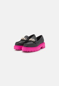 Mocassins en cuir noir avec une semelle plateforme épaisse rose et un accent de chaîne dorée sur le cou-de-pied. Présente une texture lisse et une forme arrondie.