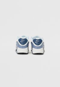 Tenisii Nike Air au un superior din piele albă și albastră, toc rotund, guler căptușit și detalii cu logo-ul specific pe spate.