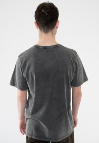 Gray short-sleeved T-shirt in a faded wash, featuring a round neckline and loose fit. Fabric appears soft with subtle texture and stitching details.