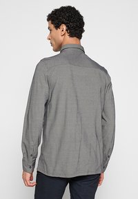 Grijs shirt met lange mouwen en een subtiele structuur, een boord met knopen, en knoopmanchetten, voorzien van een rechte zoom en een getailleerde pasvorm.