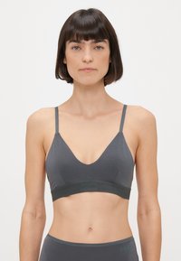 Šedý bralet s širokým elastickým pásom s nápisom "BORG". V-krk dizajn s tenkými ramienkami, vyrobený z hladkej, elastickej tkaniny.