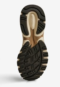 Schwarze und cremefarbene Sneaker-Sohle mit Profilmustern, einer gepolsterten Zwischensohle und dem eingravierten Markennamen "Bershka" auf der Oberfläche.