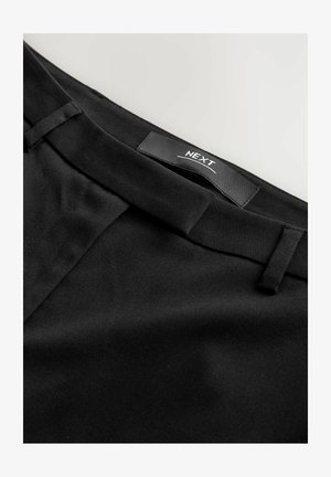 Juodos audinės kelnės su lygiu paviršiumi, išsikišusiu priekiu, diržų kilpomis ir etiketė su užrašu "NEXT" ant juosmens.