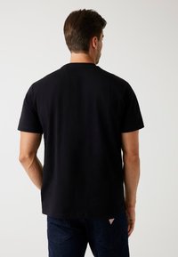 Zwarte katoenen t-shirt met korte mouwen en een ronde halslijn. Glad textuur, zonder zichtbare patronen of hardware. Casual pasvorm, eenvoudig ontwerp.