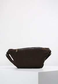 Brown fabric waist bag with a textured surface, featuring a zippered closure and an adjustable strap. Logo embossed on the front.