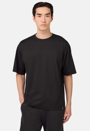 Schwarzes T-Shirt mit kurzen Ärmeln aus weichem Stoff, Rundhalsausschnitt und lockerer Passform, mit einem dezenten Markenlabel am Saum.