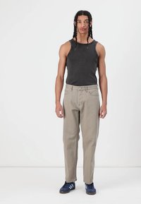 Gray tank top paired with light beige wide-leg pants. Model wears blue sneakers with white accents. Minimalist background.