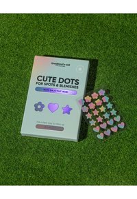 Emballage Cute Dots aux couleurs pastel douces avec des accents brillants, contenant des patches anti-acné colorés en forme d'étoile, de cœur et de fleur. 48 patches au total.