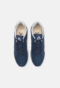 Baskets de marine avec un dessus en suède texturé et en tissu, accents blancs et lacets plats. L'intérieur est doté d'une semelle rembourrée avec un marquage.